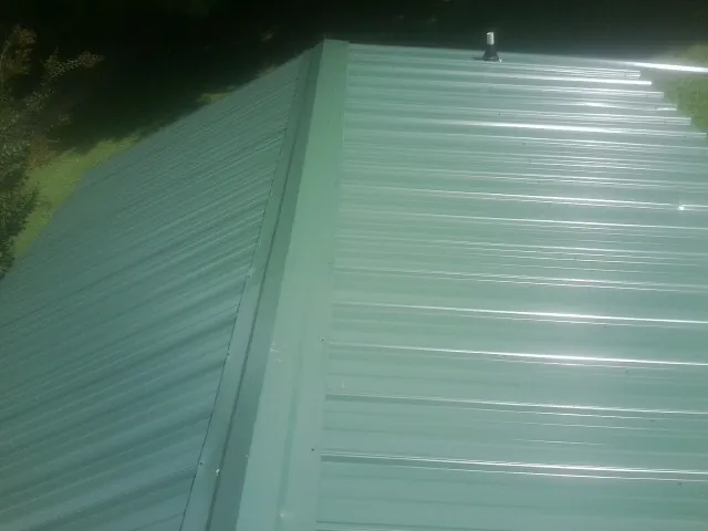 New green metal panels meeting at the ridge of a roof — Flat Roof Repair work by our crew in Holly Hill