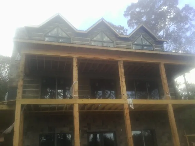 Dormers and porch framing on a large log home under construction — Roof Coating work by our crew in Holly Hill
