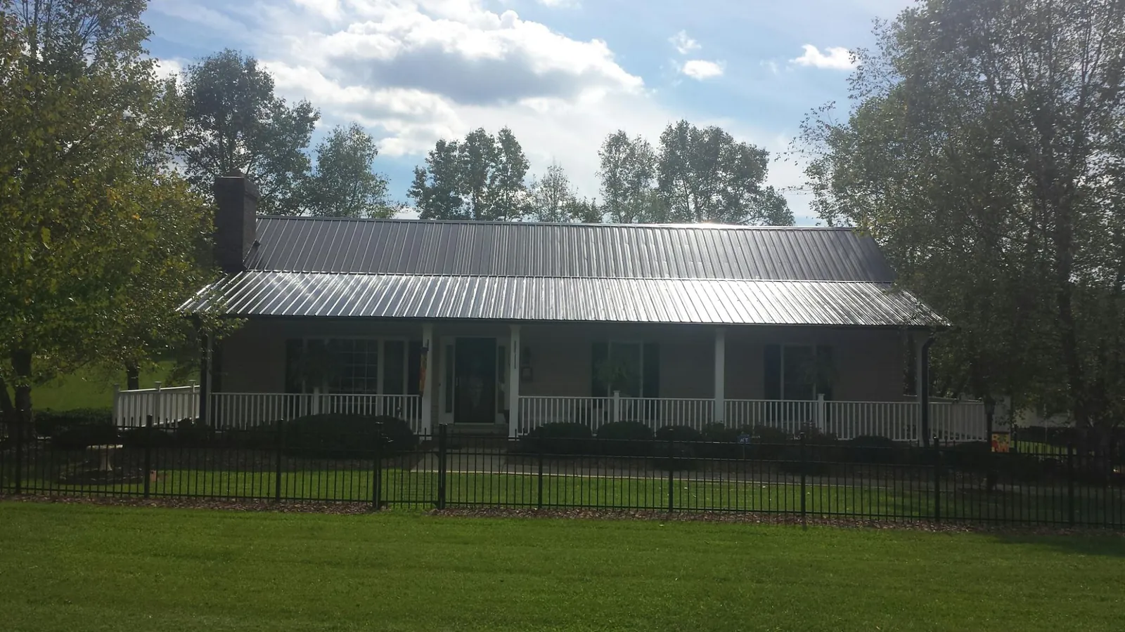 Gray metal roof on a brick ranch with a full width front porch — Gutter Guard Installation work by our crew in Holly Hill