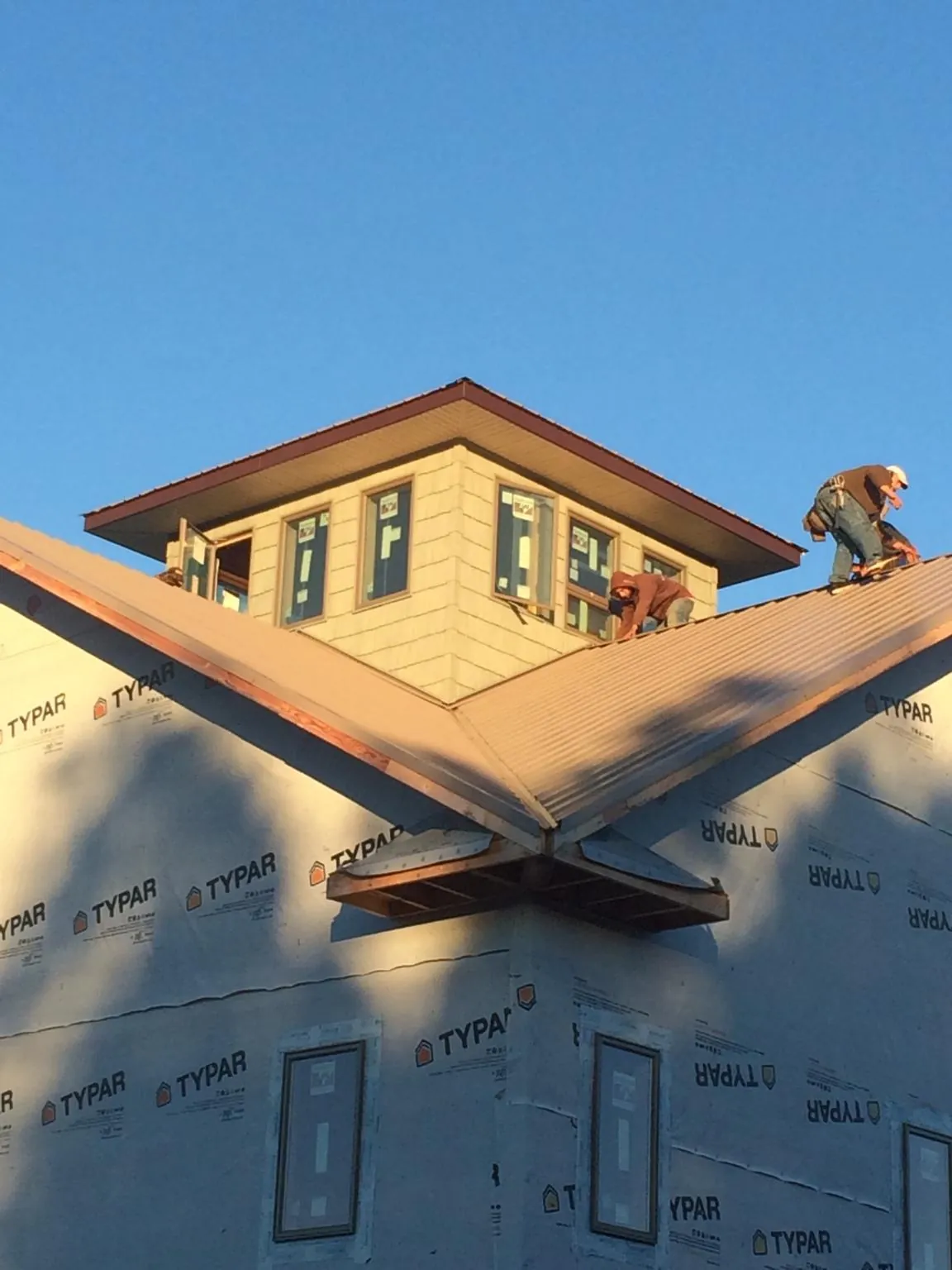 Roofers working around a rooftop cupola on a new metal roof at sunset — Roof Waterproofing in Holly Hill by Roofing Brothers